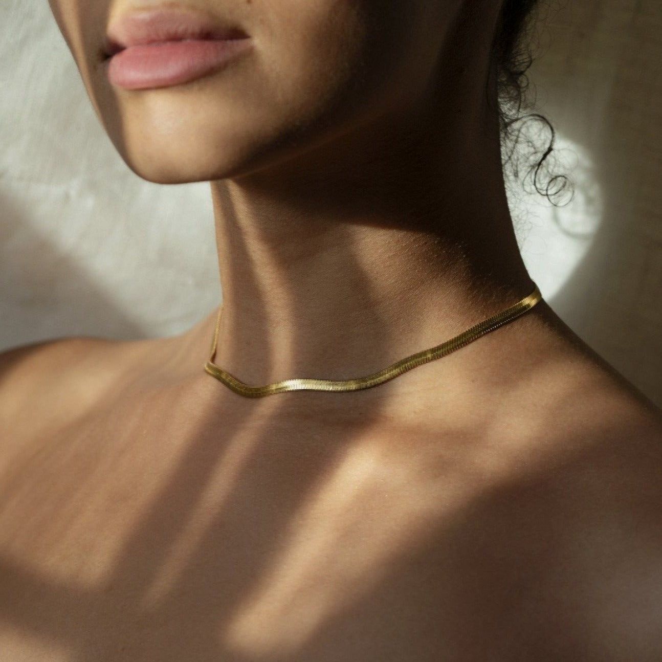Thin Loved Herringbone Snake Chain worn at the collarbone in warm summer light — Iris 1956