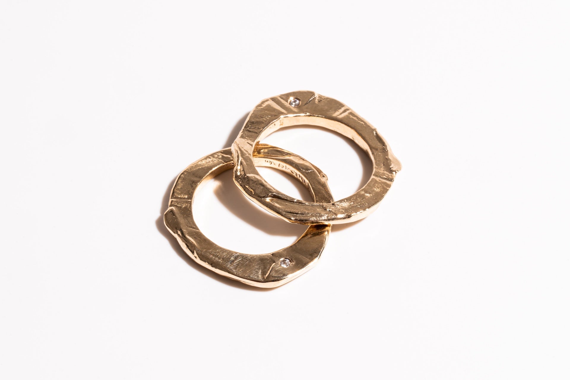 Two interlocking gold rings on a white background-iris 1956