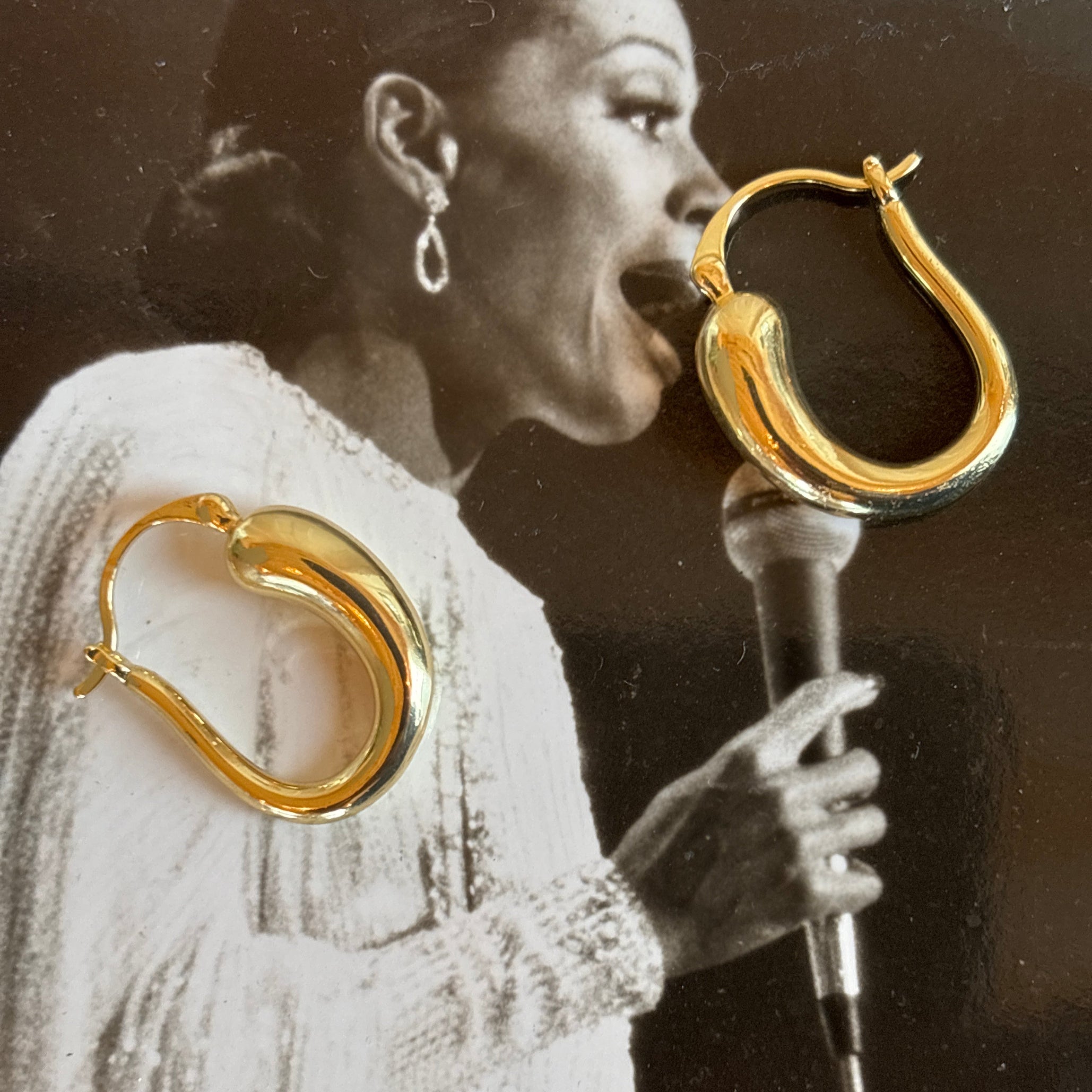 Gold hoop earrings displayed with a black and white photo of a woman wearing them.